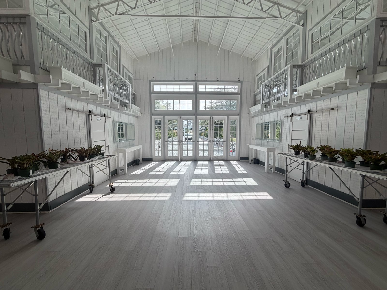 The bright empty event room at Cielo Farm with white balconies and sunlit doors