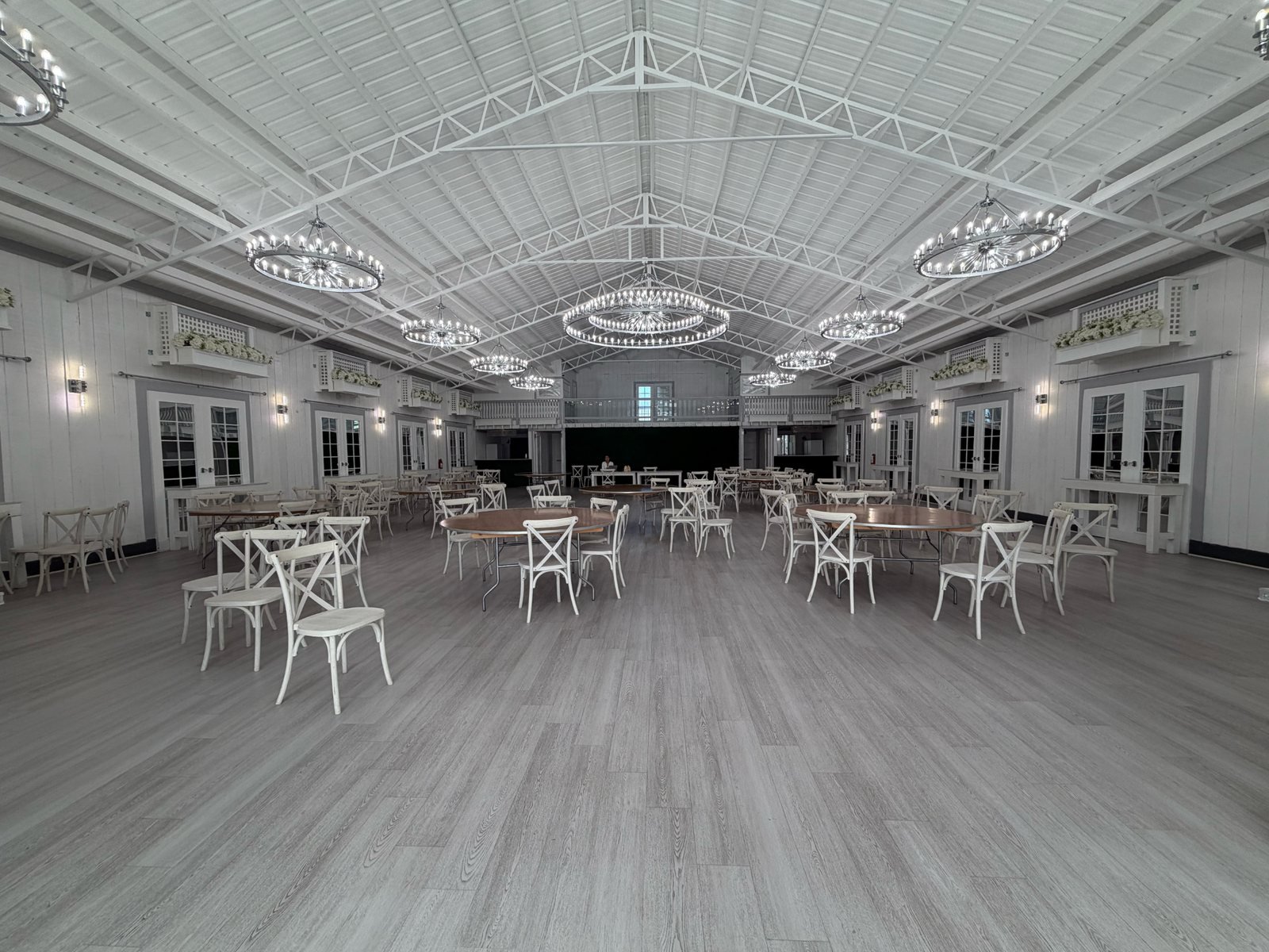 The Cielo Farm reception room arranged with tables, chairs, and illuminated chandeliers
